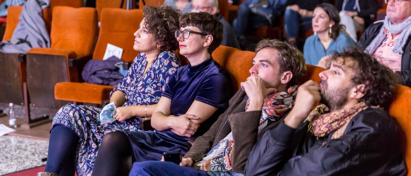 Foto Personen. Sie sitzen auf Kinost&uuml;hlen und schauen zur Leinwand