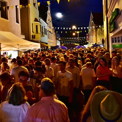 Bild vergrößern: Foto einer Menschmenge auf dem Schwandorfer Bürgerfest 2017 bei Nacht. Die Straße ist mit bunten Fahnen geschmückt und hell erleuchtet.