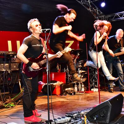 Bild vergrößern: Foto einer Rockband auf der Bühne des Bürgerfestes 2017. 2 Personen springen in die Luft.