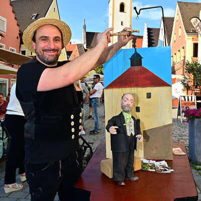 Bild vergrößern: Der Puppenspieler Michael Pöllmann präsentiert eine Marionette von Konrad Max Kunz vor einem Modell des Blasturms