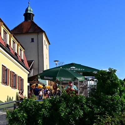 Bild vergrößern: Blick auf den Blasturm und das Türmerhaus. Daneben sind dunkelgrüne Sonnenschirme
