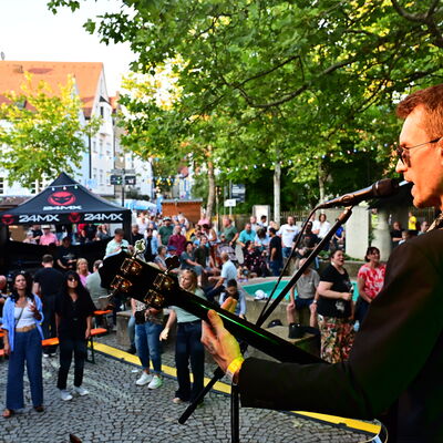 Bild vergrößern: Ein Sänger mit Gitarre performed auf der Bühne am Kolpingplatz.