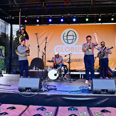Bild vergrößern: Die Band "The Dixie Hot Licks" spielt auf der Bühne im Stadtpark. Alle tragen das gleiche Outfit: Ein schwarz-weiß gestreiftes T-Shirt und rote Hosenträger