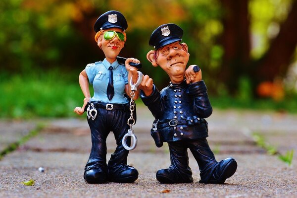 Bild vergrößern: Comicfiguren aus Plastik stehen auf dem Boden. Die Plastikpuppen stellen zwei Polizisten dar, eine Frau und einen Mann