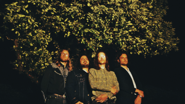 Bild vergrößern: Die vier Mitglieder der Band Midges Pocket stehen in diffusem Licht vor einem Baum.