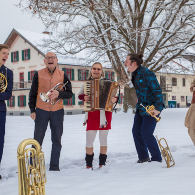Bandfoto der Unterbiberger Hofmusik. Alle f&uuml;nf Musiker stehen mit ihren Instrumenten im Schnee
