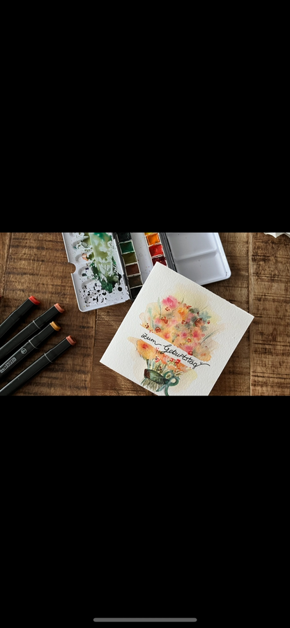 Bild vergr&ouml;&szlig;ern: Eine Karte auf die ein Blumenstrau&szlig; mit Aquarell gemalt ist daneben in Aquarellmalkasten und bunte Marker.