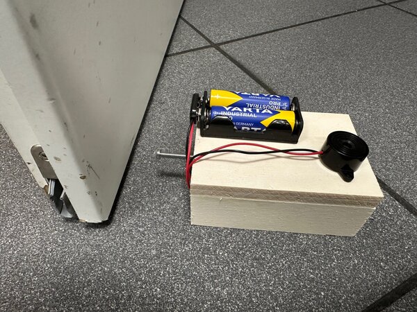 Bild vergrößern: Abbildung eines selbstgebauten Türalarms aus Holz, Drähten und Batterien.