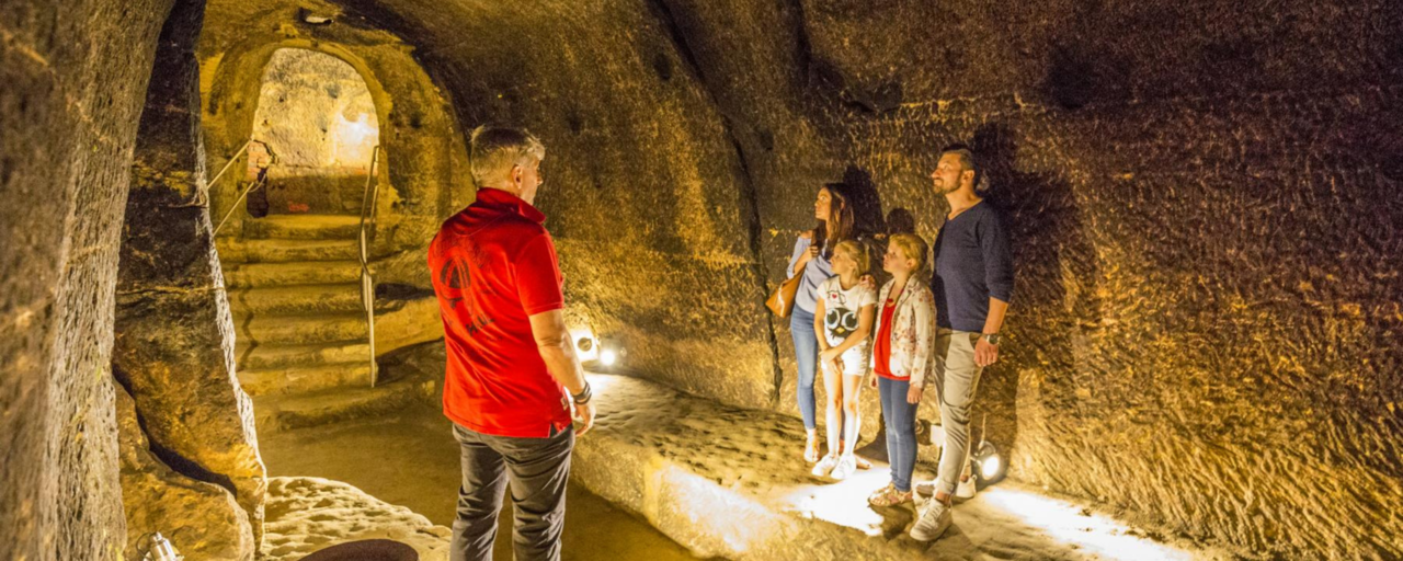 Ein Führer und eine Familie im gut beleuchteten Felsenkeller