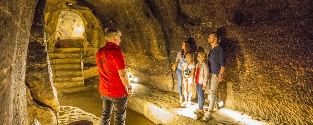 Ein Fhrer und eine Familie im gut beleuchteten Felsenkeller