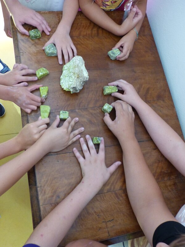 Bild vergr&ouml;&szlig;ern: mehrere Kinderh&auml;nde. Alle haben einen gr&uuml;nen Stein in der Hand