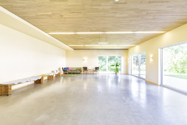 Bild vergr&ouml;&szlig;ern: Fotografie eines Raumes mit B&auml;nken die an der Wand stehen und einer offenen Fensterfront.