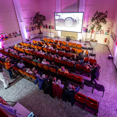 Auf dem Bild wurde das Publikum von oben fotografiert, w&auml;hrend sie einen Film auf einer Leinwand schauen, im lila beleuchteten Metropolkino.