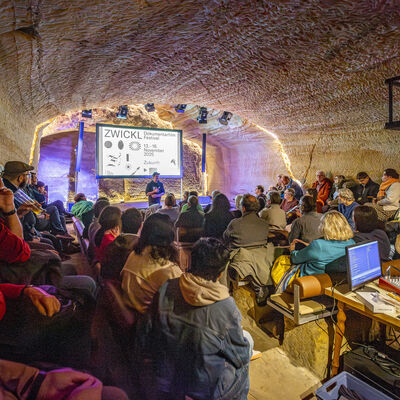 Das Publikum wurde von der linken Seite fotografiert und schaut auf die Leinwand, die im Felsenkeller aufgebaut wurde.