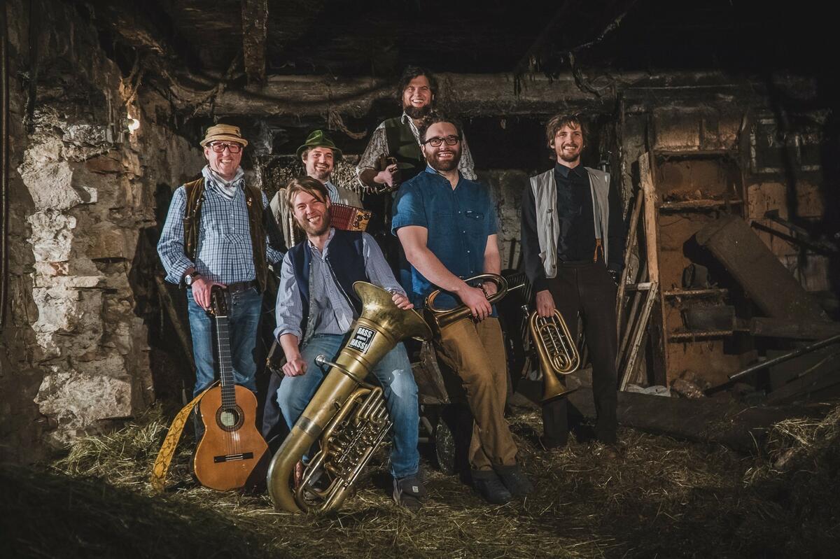Foto der Musiker der Kapelle So&So, die mit Instrumenten für das Werbefoto in einem Abriss-Haus posieren.