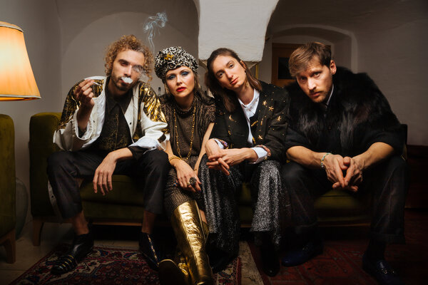 Bild vergr&ouml;&szlig;ern: Die Band "Die Nowak und die Leute aus der Raucherpause" sitzt nebeneinander auf einem Sofa. Das Bandmitglied ganz links raucht.