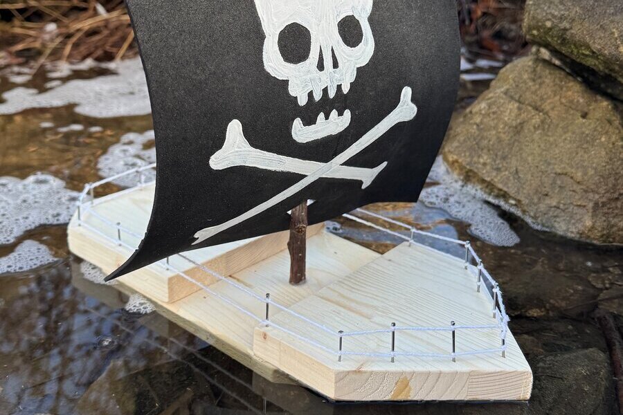 Bild vergr&ouml;&szlig;ern: kleines Holzboot im Wasser mit einem Piratensegel aus Filz