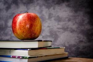 Bild vergrößern: Ein Apfel liegt auf einem Bücherstapel