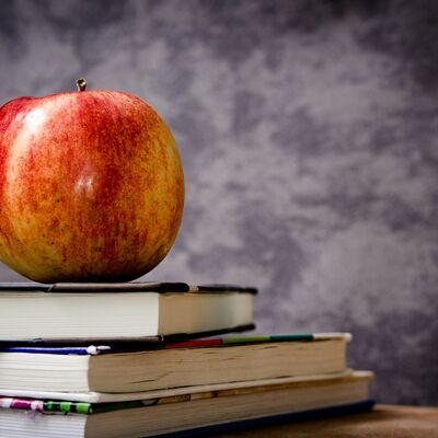 Bild vergrößern: Ein Apfel liegt auf einem Bücherstapel