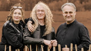 Die Drei Musiker:innen des Susi Raith Trios, Susi Raith, Jochen Goricnik und Marco Klement stehen hinter einem h&uuml;fthohen Holzzaun. &Uuml;ber dem Bild liegt ein Sepia Filter.