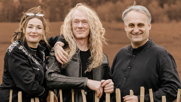 Bild vergr&ouml;&szlig;ern: Die Drei Musiker:innen des Susi Raith Trios, Susi Raith, Jochen Goricnik und Marco Klement stehen hinter einem h&uuml;fthohen Holzzaun. &Uuml;ber dem Bild liegt ein Sepia Filter.