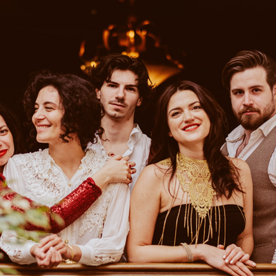 Die f&uuml;nf Musiker:innen der Band Baba Yaga stehen an einer Br&uuml;stung in einem S&auml;ulenbogen. 