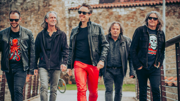 Die f&uuml;nf Musiker der Band Mad Company im Gehen fotografiert. Alle sind in Schwarz und Rot gekleidet.