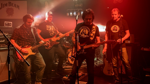 Die vier Mitglieder der Band Nez Perce mit ihren Instrumenten auf einer Rot beleuchteten B&uuml;hne. 