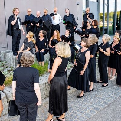 Die Mitglieder des Schwandorf Oratorienchors blicken alle zu dem Dirigenten Wolfgang Kraus. Alle sind schwarz gekleidet. 