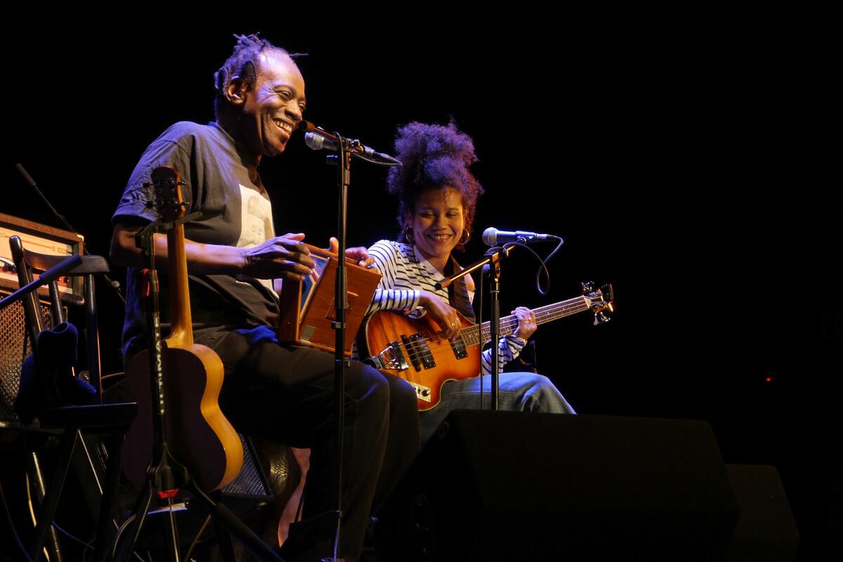 Foto von Wally und Ami Warning. Vater und Tochter spielen mit Gitarre, beide haben ein Mikrofon zum Singen.