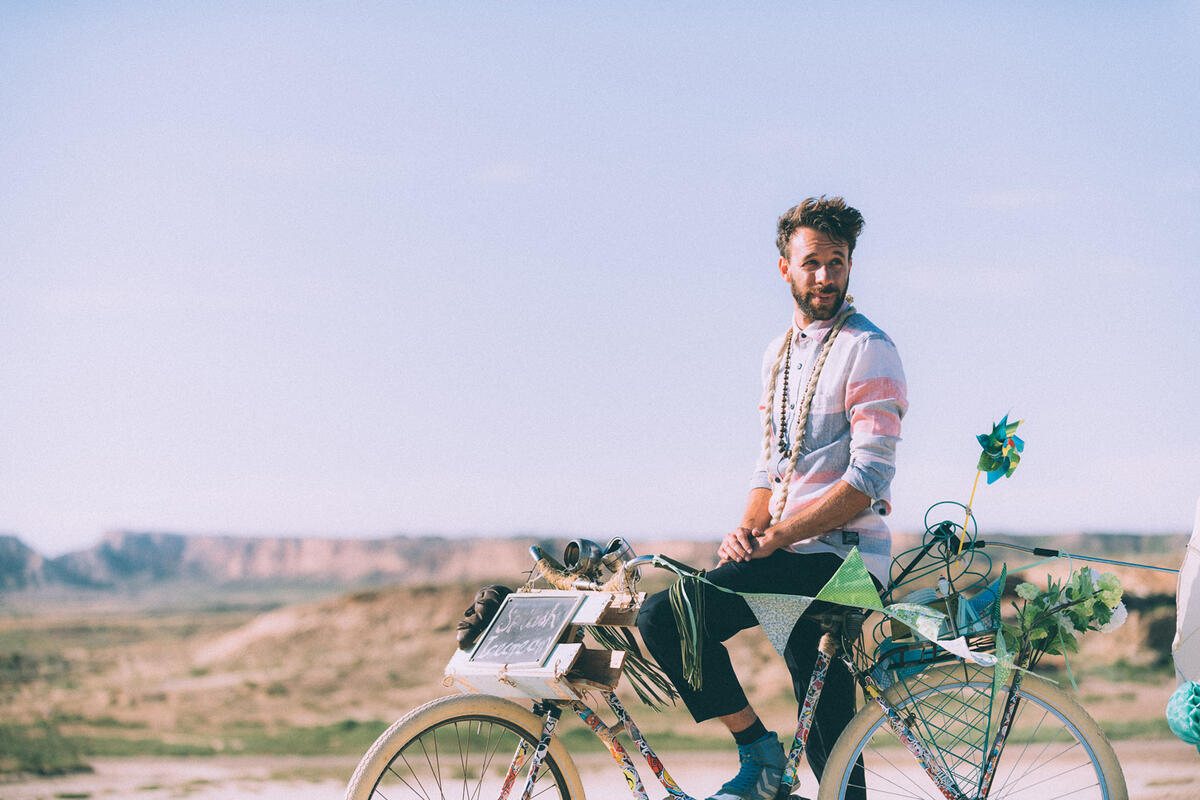 Foto von Rainer Gärtner. Der Sänger der Gruppe Impala Ray posiert auf einem Fahrrad in der Natur bei Sonnenschein.