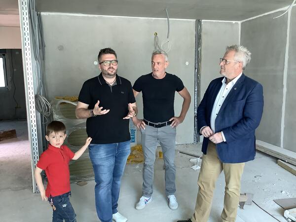 Bild vergrößern: Drei Erwachsene und ein Kind auf einer Baustelle.