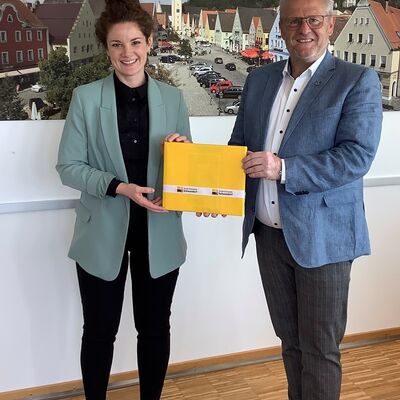 Ein Mann &uuml;bergibt einer Frau ein Buch.