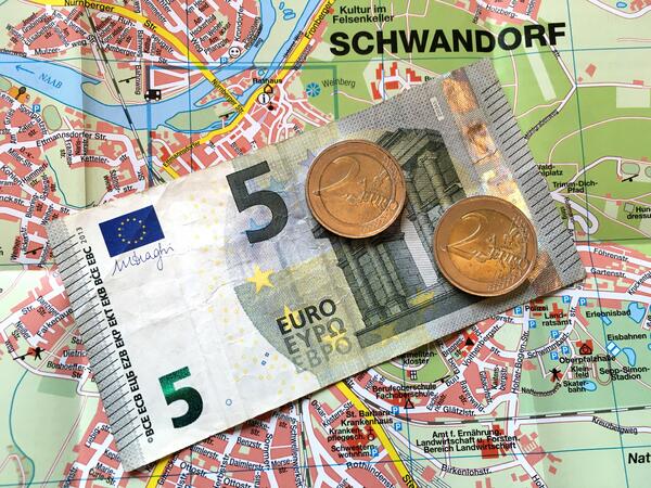 Stadtplan auf dem ein Fnf-Euro-Schein und zwei Mnzen im Wert von Zwei-Euro liegen