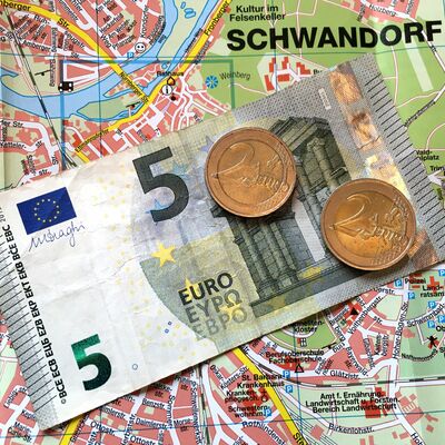Stadtplan auf dem ein Fünf-Euro-Schein und zwei Münzen im Wert von Zwei-Euro liegen